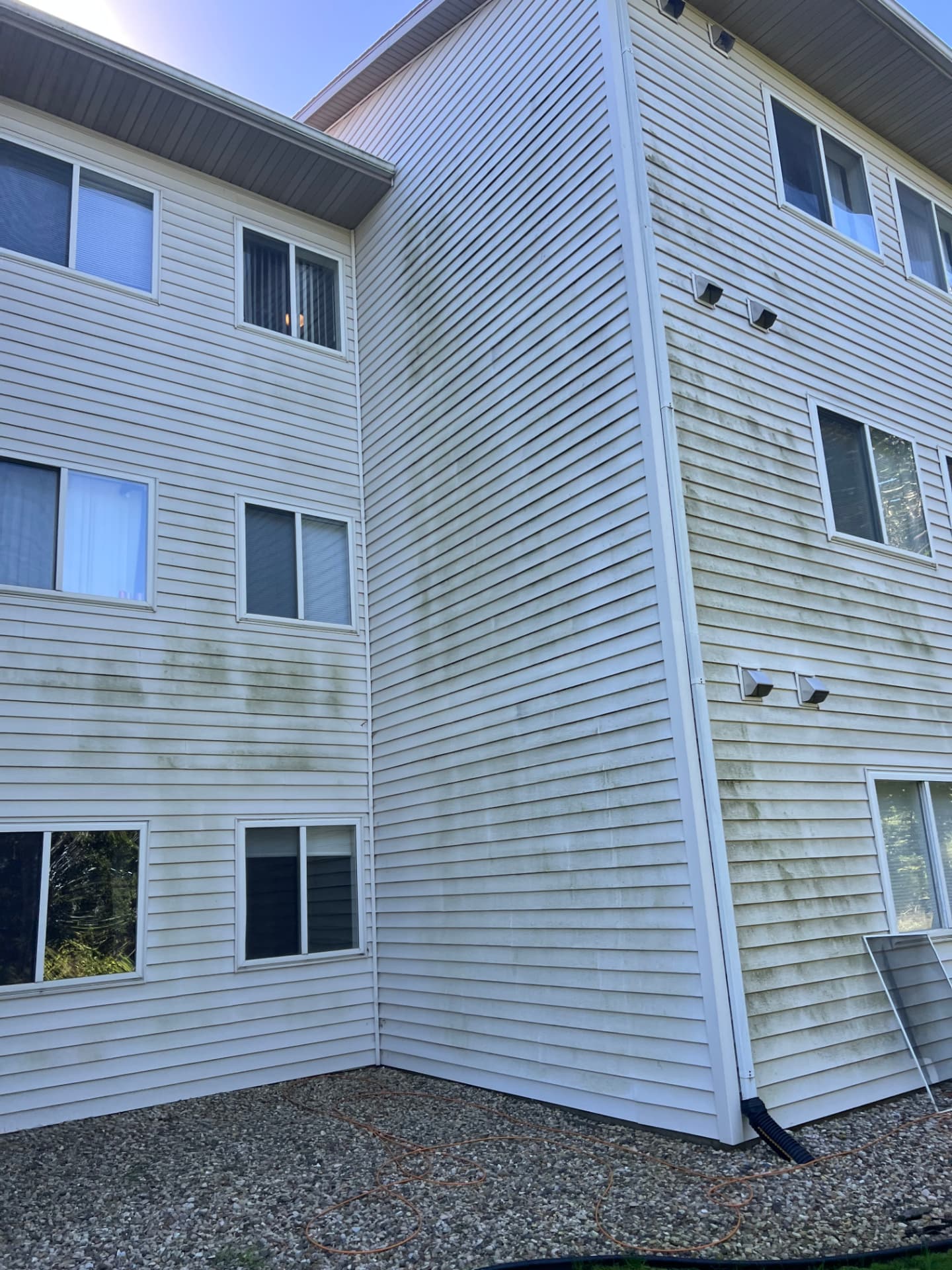 Corner of an apartment exterior showing discoloration on white siding